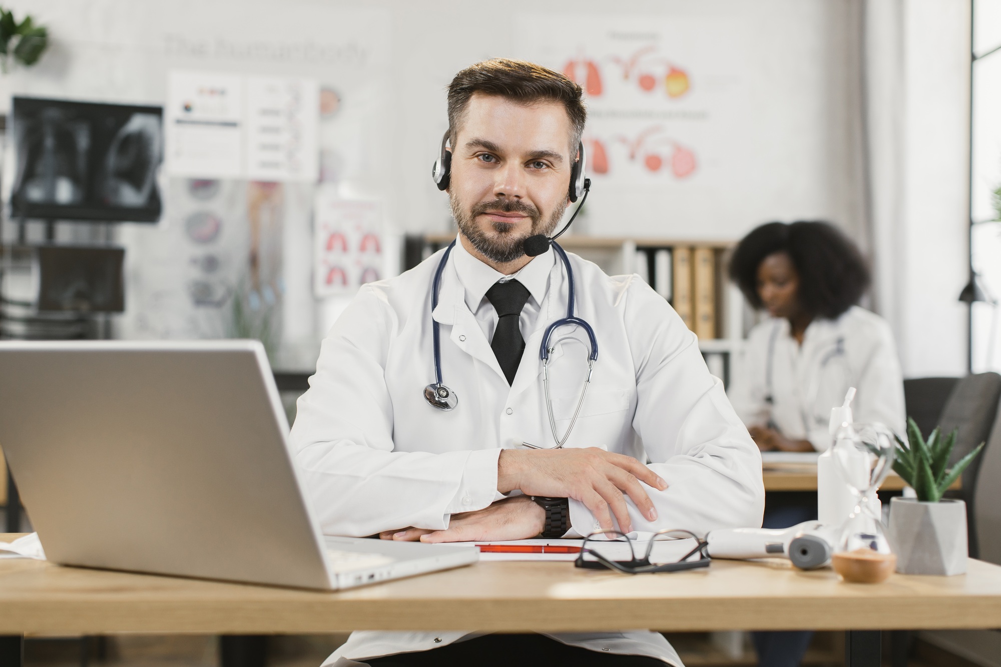 Doctor in headset having video call on laptop